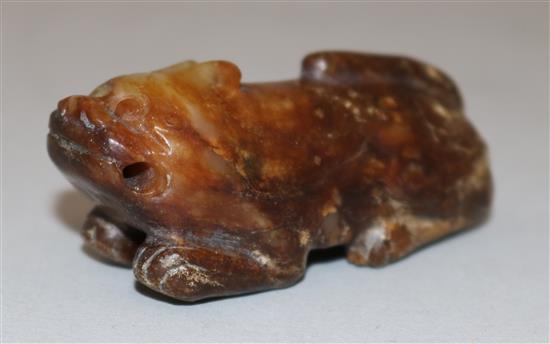 A Chinese yellow and brown jade figure of a recumbent of a lion dog, Ming dynasty or earlier, 5.7cm, calcification